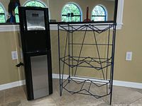 Full view of Hamilton Beach water dispenser and blue metal rack for holding multiple water jugs