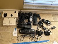 Three Logitech Harmony 900 remotes and one Harmony 890 remote alongside several IR blaster units and power adapters.