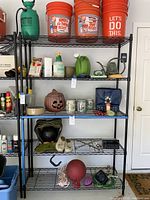 Full view of the black metal shelving unit showing five wire shelves loaded with various unrelated items for scale only.