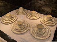 Six complete place settings each with tea cup on saucer, salad plate, dinner plate arranged on towel