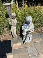 Both statues outdoors on paver patio with grass backdrop