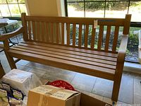 Full front view of teak bench showing slatted seat, back, armrests