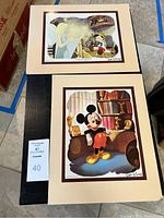 Pair of vintage Walt Disney prints on cream matte with brown border. Top print features Pinocchio and the Blue Fairy, lower print features Mickey Mouse in front of bookshelf.