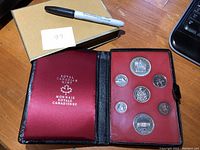 Full view of the open original black leather case with insert showing all seven coins and Royal Canadian Mint branding inside the lid.