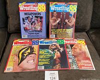 Photo showing five wrestling magazines arranged on a couch, covers visible with various wrestlers including Megapowers and Sting.