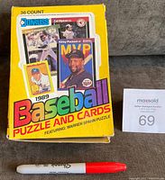 Front view of the closed 1989 Donruss Baseball Puzzle and Cards wax box next to a marker for size comparison, showing box condition and design.