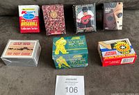 Full lot of seven factory boxed and sealed card sets displayed on a couch, showing all box titles and condition.