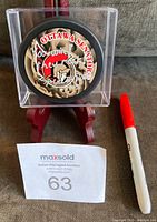 Front view of Ottawa Senators signed hockey puck in clear plastic holder on red stand with red marker for scale.