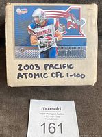 Box labeled 2003 Pacific Atomic CFL 1-100 with Montreal Alouettes Ben Cahoon card on top