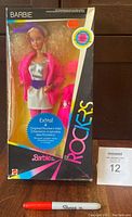 Front view of Barbie And The Rockers unopened boxed doll showing Barbie dressed in rocker costume with distinct pink jacket, silver top and purple belt and box graphics.