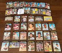 Wide shot of many 1971 O.P.C. baseball cards fanned and grouped on floor showing multiple players and team cards.