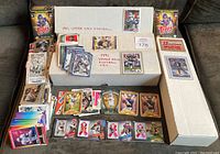 Overview of the football cards including 1991 Upper Deck near complete set in a box and 2005 Bowman near complete set boxed, multiple loose cards spread out around.