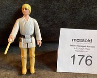 Front view of vintage Luke Skywalker action figure standing upright, holding telescoping lightsaber.