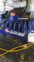 Side view showing Campbell Hausfeld logo and coiled air hose on blue tank