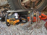 Photo showing two chainsaws (Poulan Pro and Husqvarna) side by side with loose chains placed on top and ground. The Poulan Pro is yellow and black, Husqvarna orange and black.