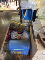 Blue Mastercraft air compressor showing front gauges, controls and tank branding.