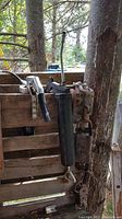 Photo of grease gun and two come-along hand winch tools hanging on wood fence outdoors.