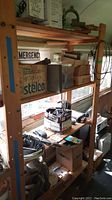 Wide view of wooden shelves holding boxes, tools, and hardware items near a window.