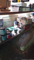 Wide view of assorted paint cans, jars with hardware, and adhesive products on surface