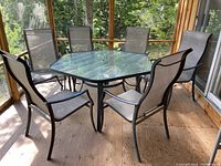 Full view of hexagonal glass-top table with six matching chairs on a screened porch