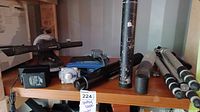 Various spotting scopes, tripods, and accessories on a shelf showing condition and quantity