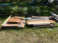 Two pallets with various scrap wood pieces stacked in the grass outside, showing overall lot.