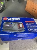 Box of Campbell Hausfeld 12V tire inflator. Blue box shows product photo and specifications.