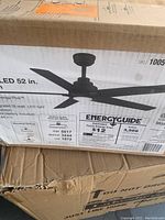 Box of a 52-inch ceiling fan with integrated LED light showing fan image and energy guide details