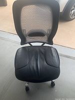 Front view of black office chair showing padded leather seat and mesh backrest.