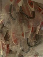Pile of sealed clip-on reading lights, mostly white and red colored with spring clips.