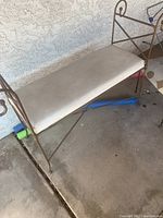 Ornate metal bench with vinyl seat cushion showing metal frame and vinyl seat needing cleaning.
