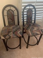 Pair of Southwestern design upholstered barstools with metal frames, patterned fabric seats and backs, and circular footrests.
