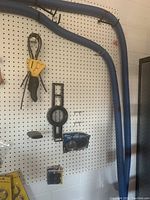 View of pegboard wall with yellow-handled tool, tape rolls, and hanging blue tubing