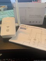 Front view of OurLink Wi-Fi range extender showing LEDs, antennas, packaging, and quick installation guide.