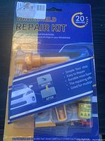Front view of windshield repair kit packaging showing resin injector and branding information.