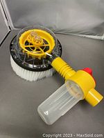 Yellow and black rotary brush with white bristles and clear detergent container. Close-up showing rotary gear mechanism.