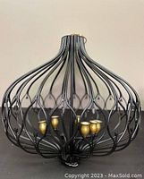 Front view of the vintage chandelier showing open cage shaped black metal bars and 4 brass finish bulb cups.