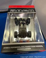 Front view of the black mini remote control racing car inside original packaging, showing protective plastic and product features on box.