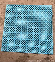 Top view of a blue plastic interlocking drainage floor tile showing lattice pattern.