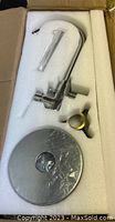 VEVOR freestanding tub filler faucet components in protective foam packaging within a cardboard box. Visible chrome plated parts including tall faucet spout, lever handle, mounting flange, and circular base plate.