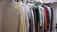 Photo of assorted women's clothing items hanging on a rod, including skirts, blouses, and coats in varied colors