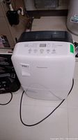 White and black Garrison dehumidifier unit shown from front with control panel and power cord lying on floor.