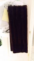 Dark brown mink fur stole hanging on a door showing full length.