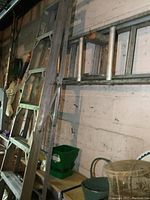 Aluminum 8 ft step ladder with wide steps and side rails leaning against a wall in a garage setting.