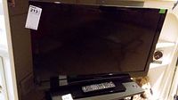 Front view of 32 inch Panasonic TV with remote control on the stand.