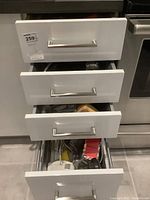 Four kitchen drawers with various utensils and kitchen tools visible, including the hand mixer and potato ricer.