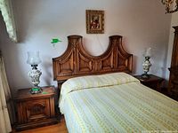 Pair of vintage Capodimonte lamps on wooden bedside tables next to a bed with a wooden carved headboard.