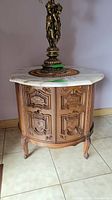 Full view showing octagonal marble top, wooden base with carved details, and curved legs.