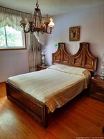 Queen size bed frame shown with decorative carved wood headboard and footboard, yellow patterned bedspread on mattress for display only