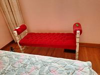 Front angled view showing the tufted red velvet upholstered seat and arms with white turned wood frame and legs.